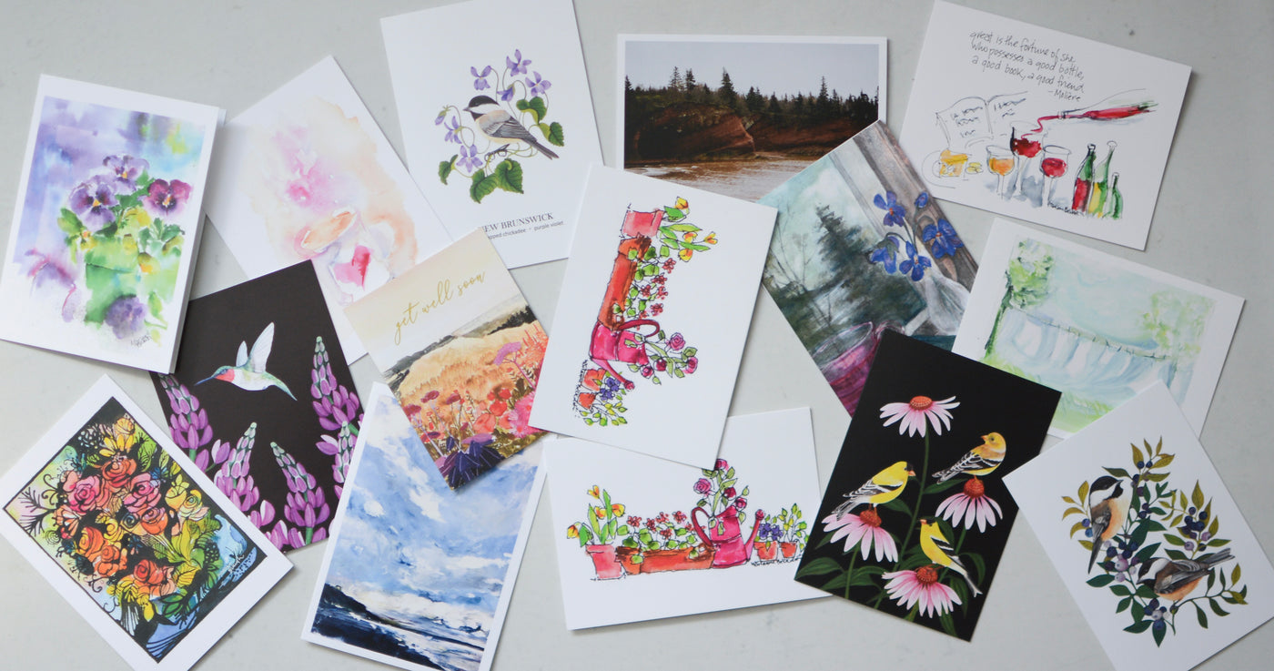 A variety of colorful greeting cards featuring local art and designs, available at Rising Tide Gifts.